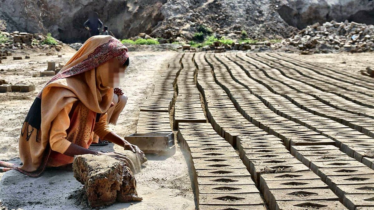 A brick kiln in Punjab, Pakistan: rows of raw bricks drying beside the chimney