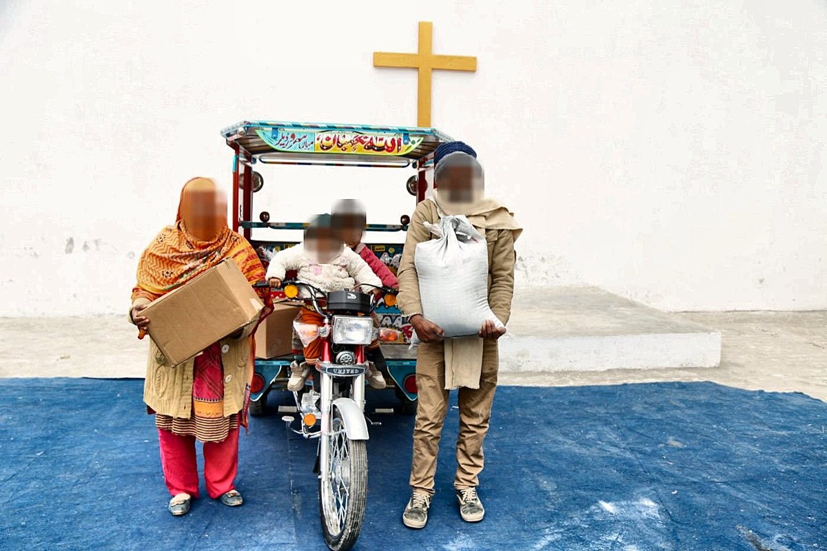 A freed family with food, a rickshaw and a new start, standing under a cross